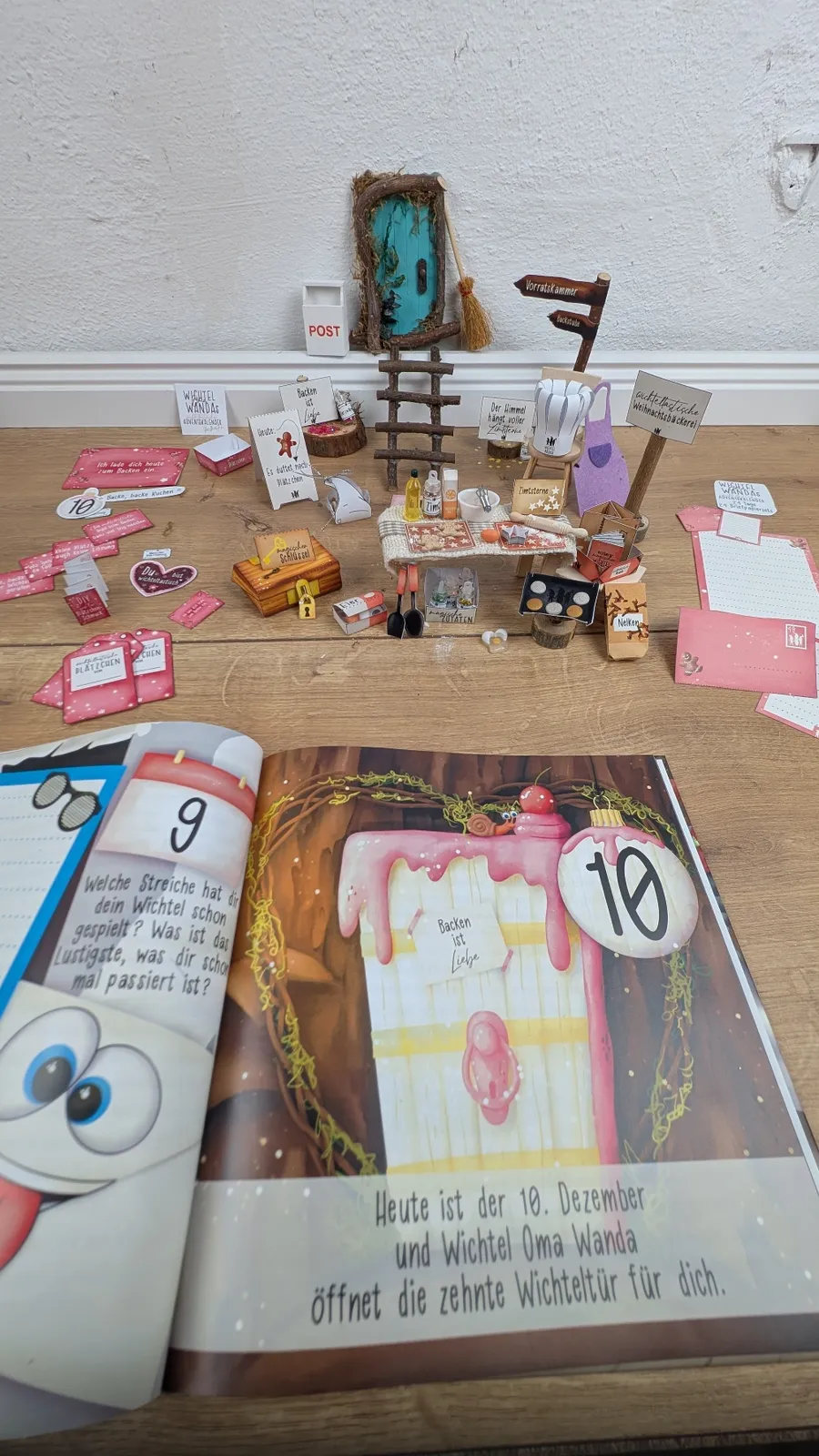 Aufgeschlagenes Adventskalender-Buch Weihnachten bei den Wichteln neben der Backszene