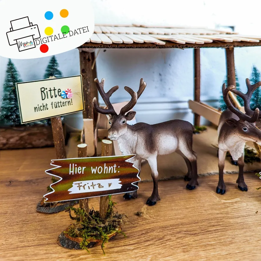 Zwei Rentierfiguren vor einem kleinen Holzstall mit den Schildern Bitte nicht füttern und Hier wohnt: Fritz, aus dem Wichtel Rentier Parkplatz Set