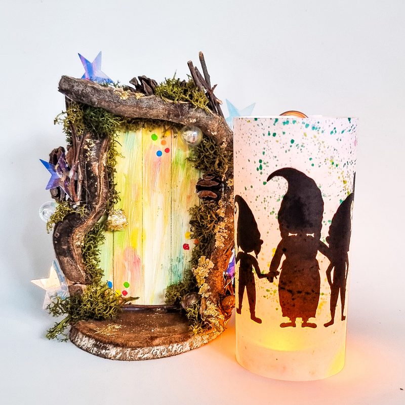 Wichtelrufer aus dem Starterpaket: leuchtende Laterne mit Wichtel-Silhouetten neben einer bunten Wichteltür