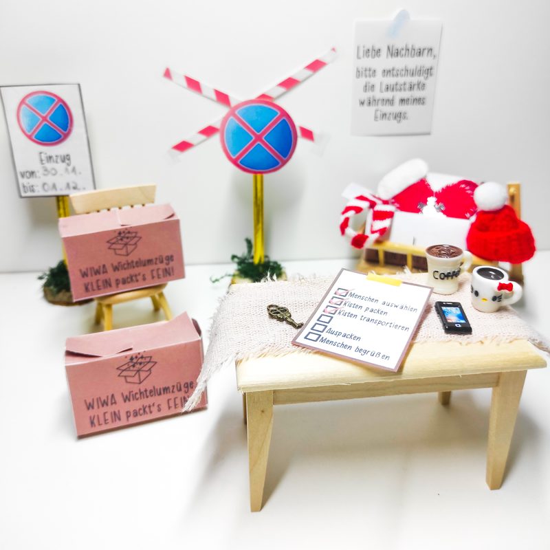 Einzugsset aus dem Starterpaket: Miniatur-Umzugsszene mit Umzugskartons, Schildern und der Checkliste des Wichtels